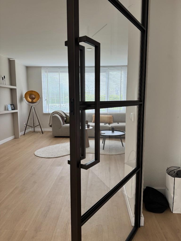 Zwarte stalen binnendeur met glas, open naar de woonkamer